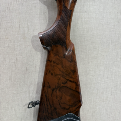 Coronha de arma de caça em madeira com detalhes metálicos prateados e gatilho dourado