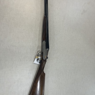 Espingarda de canos duplos em madeira e metal encostada numa parede clara