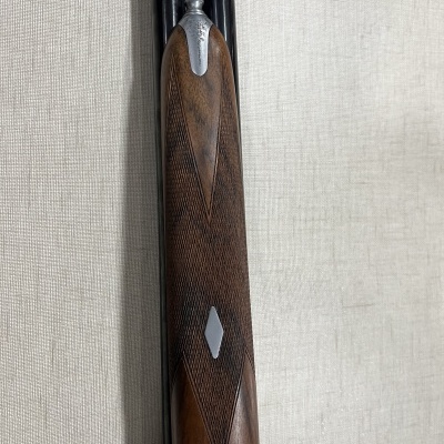 Arma de fogo com canos pretos e empunhadura de madeira castanha texturizada