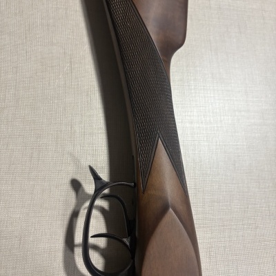 Coronha de arma de fogo em madeira castanha com gatilho preto sobre superfície clara