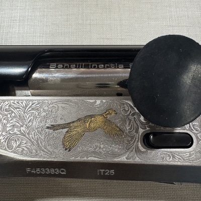 Parte decorada de uma espingarda Benelli com imagem de faisão e texto gravado