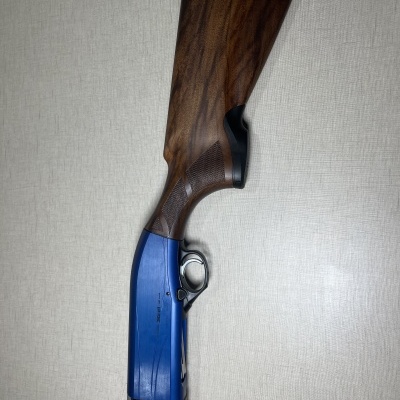 Espingarda de madeira e metal azul em fundo cinza claro