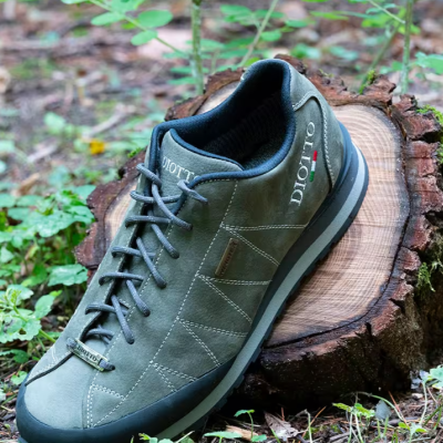 Tênis verde oliva com sola preta e logótipo DIOTTO sobre tronco no bosque