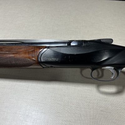 Espingarda de caça com madeira castanha e metal preto sobre superfície clara