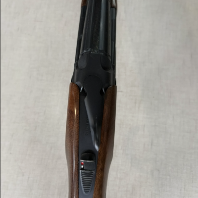 Espingarda de canos duplos em madeira e metal preto vista de cima.