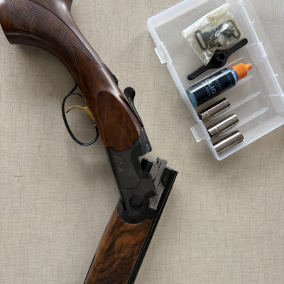Espingarda de cano duplo com acessórios numa caixa plástica