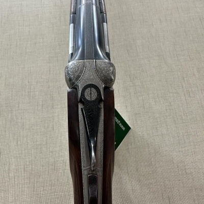 Rifle de caça com madeira escura e metal prateado com gravações