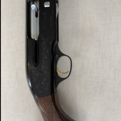 Espingarda em madeira castanha e metal preto com gravações, gatilho dourado e texto 'P. Beretta MADE IN ITALY'