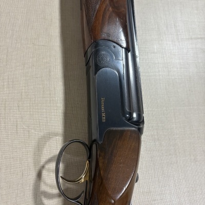 Espingarda de caça Perazzi MX8 com madeira castanha e metal negro sobre fundo bege