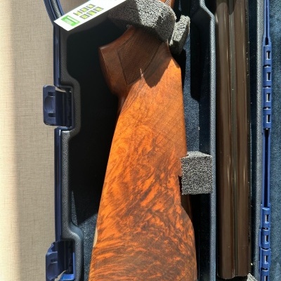 Espingarda com coronha de madeira castanha guardada em mala azul com espuma cinza