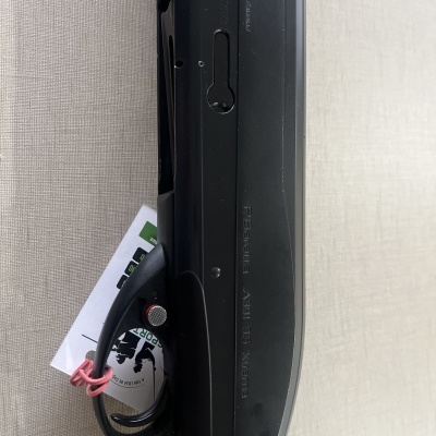 Espingarda preta sobre tecido bege com etiqueta presa