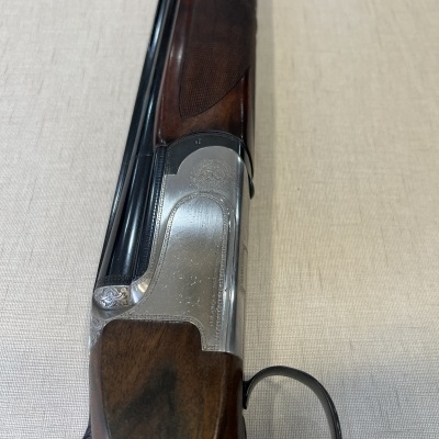 Espingarda de cano duplo com coronha em madeira castanha sobre tecido bege