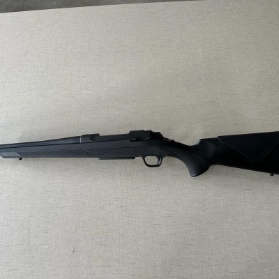 Espingarda preta com coronha sintética sobre superfície clara