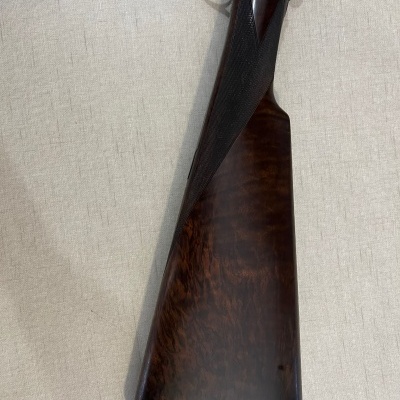 Espingarda com coronha em madeira castanha escura e detalhes gravados