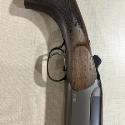 Arma com coronha de madeira e metal cinzento com texto F16