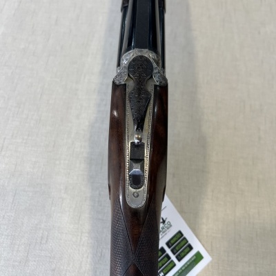 Espingarda dupla com coronha de madeira escura e detalhes metálicos gravados vista superior.