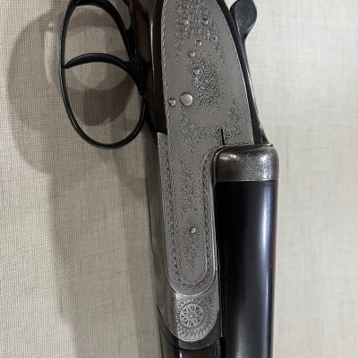 Rifle de canos duplos com detalhes em metal gravado e coronha em madeira escura