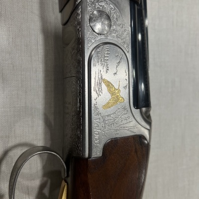 Espingarda de cano duplo com gravações decorativas e madeira escura.