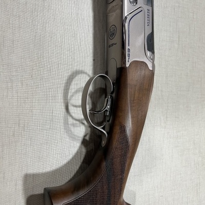 Espingarda Beretta de madeira e metal sobre tecido claro