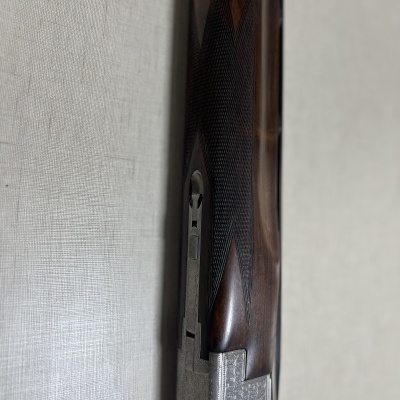 Cano de espingarda em madeira escura e metal prateado com textura martelada