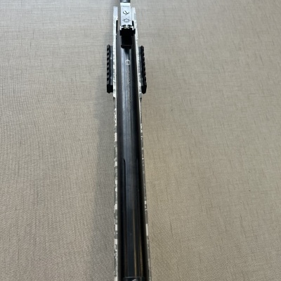 Arma de fogo com coronha camuflada e cano cinza sobre fundo cinzento