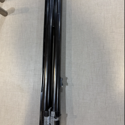 Conjunto de canos duplos de arma de fogo com acabamento preto e prateado sobre tecido cinza