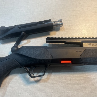 Espingarda Beretta preta desmontada com partes metálicas e texto gravado