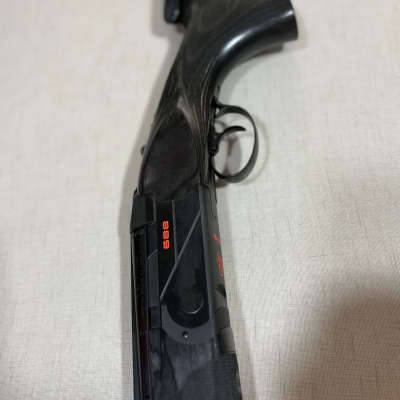 Espingarda com coronha preta em madeira e metal preto com texto laranja.