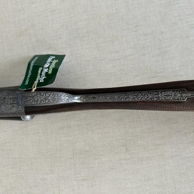 detalle da arma de caça com madeira escura e metal gravado com etiqueta verde