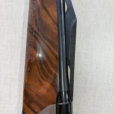 Rifle ou espingarda com coronha de madeira castanha e armação preta com gravação e texto