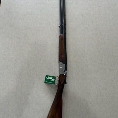 Espingarda de cano duplo com madeira castanha e metal prateado e preto com etiqueta verde