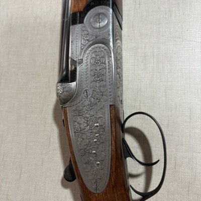 Espingarda em madeira e metal com padrões gravados e gatilho duplo