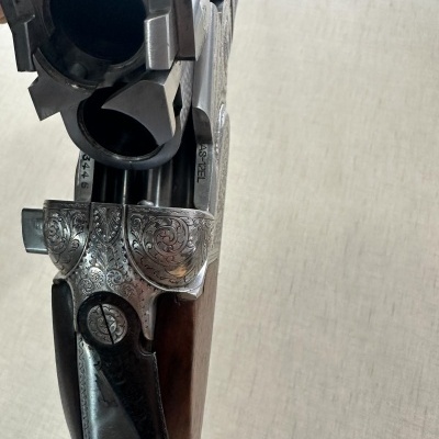Espingarda de canos duplos com detalhes gravados e cabo em madeira escura