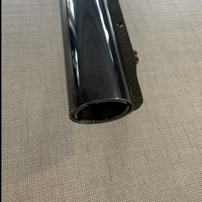 Tubo cilíndrico preto brilhante sobre superfície bege quadriculada