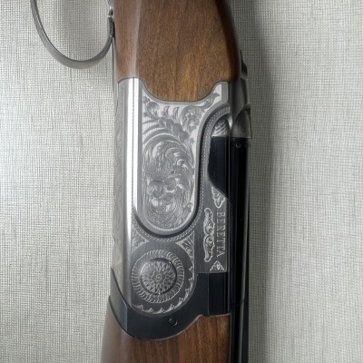 Espingarda com empunhadura em madeira castanha e lado metálico prateado gravado com texto BERETTA