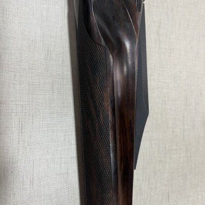 Coronha de madeira escura com textura tipo xadrez encostada em parede clara