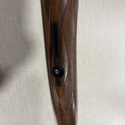 Culata de madeira com textura em padrão xadrez e peça metálica preta decorada