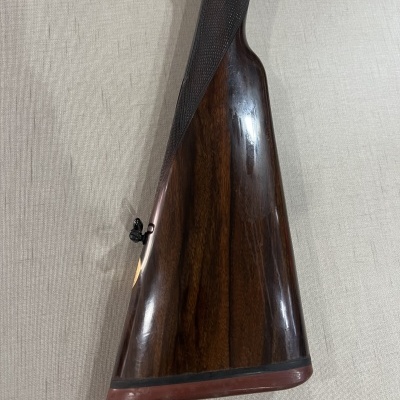 Coronha de espingarda em madeira escura polida com textura entalhada e apoio de borracha vermelha