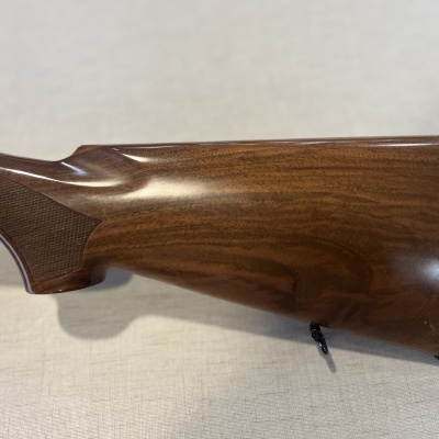 Coronha de espingarda em madeira castanha polida com detalhes canelados e suporte para alça