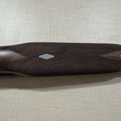 Espingarda com madeira escura trabalhada e detalhes metálicos gravados