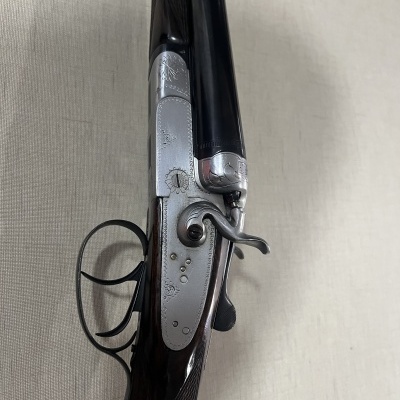 Rifle de canos duplos em metal prateado e madeira escura com detalhes decorativos