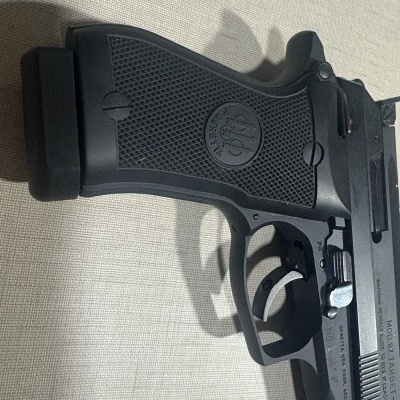 Pistola Beretta preta com empunhadura texturizada e texto gravado no slide