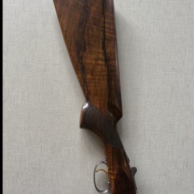 Coronha de espingarda em madeira escura polida com detalhes metálicos e gatilho dourado