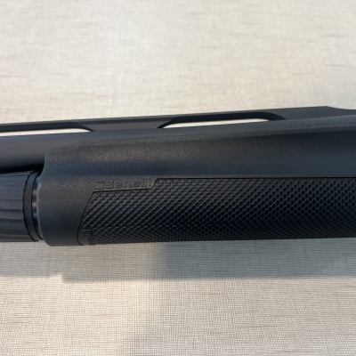 Parte de arma de fogo preta com textura antiderrapante num fundo claro