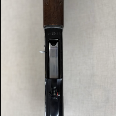 Espingarda com coronha de madeira e partes metálicas pretas vista de cima