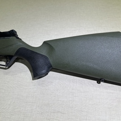 Espingarda com coronha verde escuro e preto sobre fundo neutro