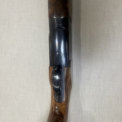 Espingarda de cano duplo em madeira e metal sobre tecido branco