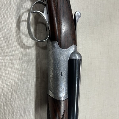 Espingarda com canos laterais e empunhadura em madeira escura com detalhes gravados