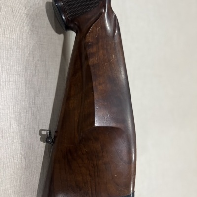 Coronha de madeira escura com acabamento polido e detalhe metálico para correia