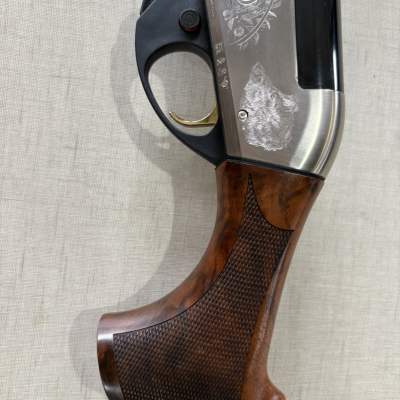 Parte da coronha em madeira com punho em metal gravado, fundo neutro